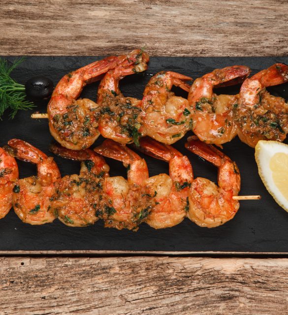 Japanese cuisine. Fried shrimps served on black slate with herbs and lemon, top view. Restaurant menu photo.