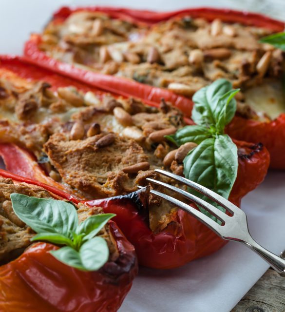 Closeup shot of baked peppers stuffed with tuna fish, mozzarella cheese and pine seeds.