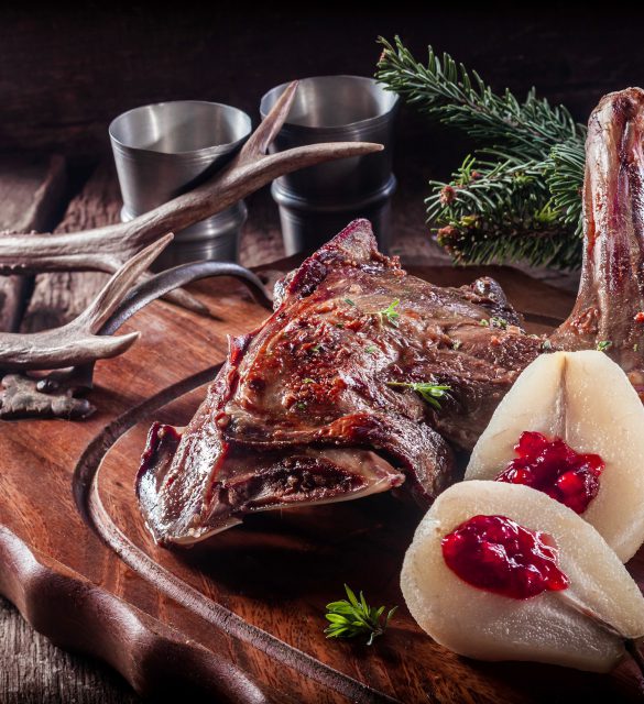 Roasted Vension Haunch Served on Wooden Tray with Prepared Pears Accented by Evergreen Sprigs and Deer Antlers