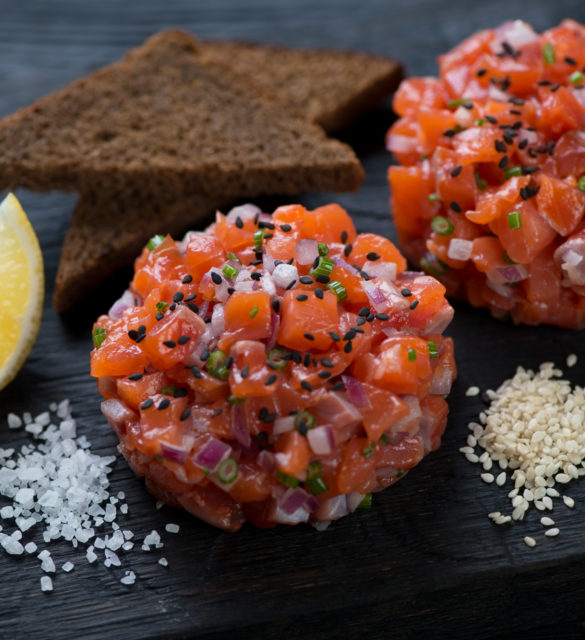 Close-up of salmon tartare served with sesame, bread and lemon
