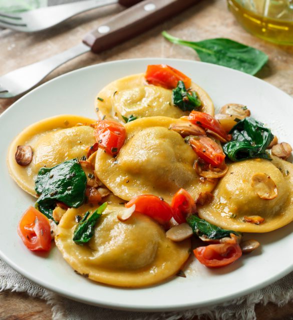 Ravioli with spinach and mushrooms on a wooden background